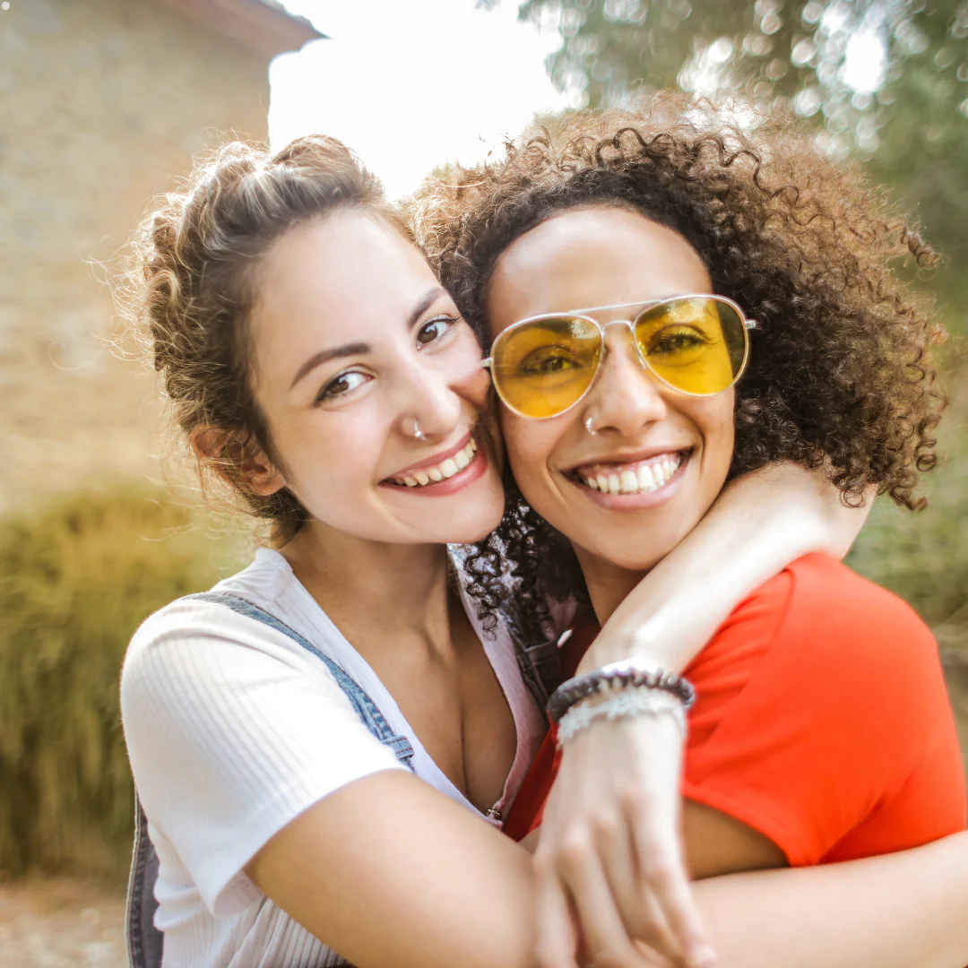 Two smiling travel nurses embracing outdoors, symbolizing support and friendship while working with multiple healthcare staffing agencies