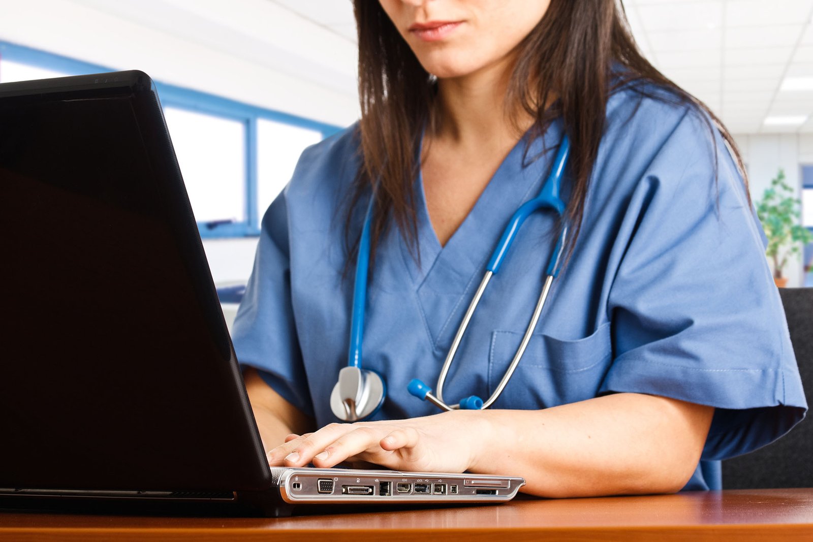 Nurse working on laptop in a hospital setting for staffing coordination
