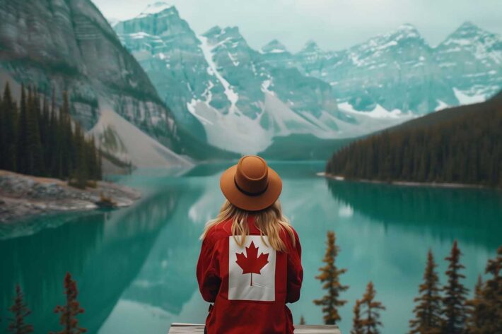travel nurse wearing a Canadian flag backpack looking at a turquoise mountain lake in the Canadian Rockies.