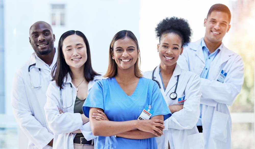 Group of smiling healthcare professionals including nurses and doctors standing together