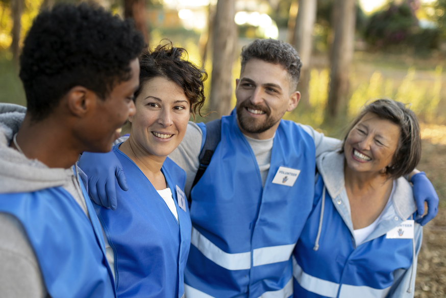 A group of bilingual travel nurses smiling and talking outdoors while wearing blue uniforms, representing teamwork, diversity, and collaboration in Canadian healthcare.