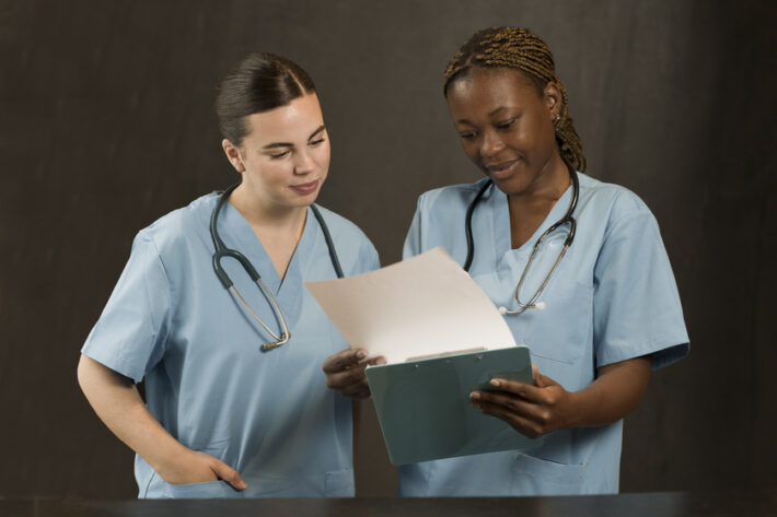 allied healthcare staffing - white and black nurse looking at a book