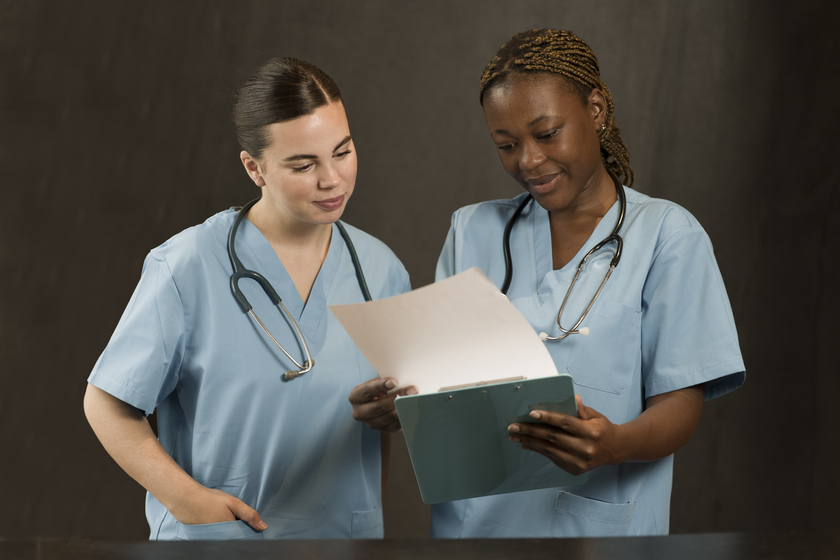 allied healthcare staffing - white and black nurse looking at a book