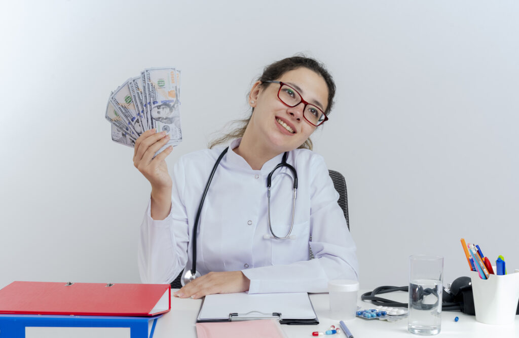 Nurses earn in Canada - white smiling nurse displaying cash